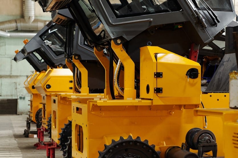 Several huge construction machines of yellow color standing in row